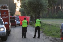 Miejsce wypadku drogowego na trasie Boruja - Chrośnica, w którym śmierć poniósł 39-letni mężczyzna kierujący motocyklem Yamaha. Na pierwszym planie policjanci obsługujący zdarzenie, w tle parawan zasłaniający ciało ofiary.