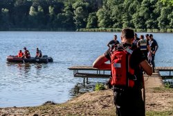 Funkcjonariusze straży pożarnej, policji oraz ratownicy medyczni podczas działań na jeziorze w Wąchabnie prowadzonych w związku ze zgłoszonym zaginięciem młodego mężczyzny.