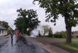 Strażak, podczas gaszenia auta, które stanęło w płomieniach po uderzeniu w drzewo.