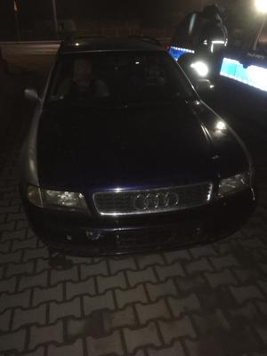 Sceneria nocna. Widoczny samochód osobowy marki Audi.Obok oznakowany radiowóz i stojący przy nim policjant.