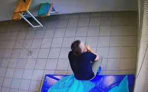 Mężczyzna zatrzymany w związku z nienależytym sprawowaniem opieki nad dwójką 9-miesięcznych dzieci. Mężczyzna siedzi na materacu, odwrócony plecami do wykonującego zdjęcie.