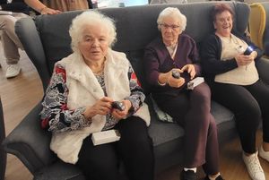 Seniorki siedzące na kanapie prezentują otrzymane minilatarki
