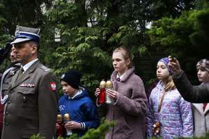 Dzieci stojące pod pomnikiem ze zniczami w rękach. Na pierwszym planie umundurowany żołnierz Wojska Polskiego w stopniu pułkownika.
