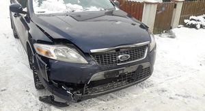 Sceneria zimowa. Śnieg. Uszkodzony przód granatowego Forda Mondeo.