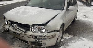 Sceneria zimowa. Śnieg. Widok na uszkodzony pas przedni samochodu Volkswagen Golf koloru srebrnego.
