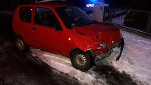 Sceneria zimowa. Śnieg. Uszkodzony pas przedni Fiata Seicento w kolorze czerwonym