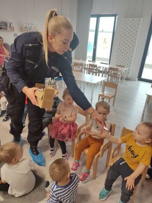 Policjantka rozdaje dzieciom elementy odblaskowe