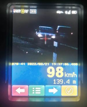Zbliżenie na ekran wideorejestratora, Sceneria nocna, widoczny zarys samochodu, znacznik wskazujący obiekt poddany pomiarowi oraz prędkość 98 km/h.