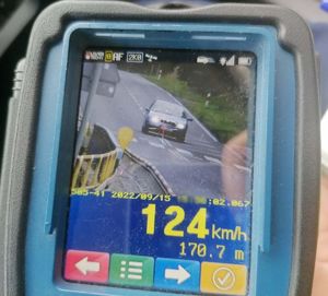 Widok ekranu wideorejestratora. Na ekranie widoczne auto, pod nim wyświetlona prędkość 124 km/h i data.