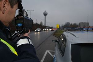Policjant Wydziału Ruchu Drogowego podczas kontroli prędkości kierujących pojazdami. Zbliżenie na ekran urządzenia pomiarowego.