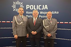 Uhonorowani medalami policjanci pozują do zdjęcia w towarzystwie Starosty Wolsztyńskiego na tle baneru Komendy Wojewódzkiej Policji w Poznaniu.