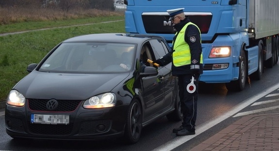 Wolsztyn - droga krajowa nr 32. Policjant stoi przy samochodzie osobowym i przeprowadza badanie trzeźwości kierującego. W tle samochód ciężarowy.
