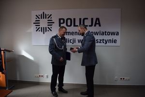 Uroczystość pożegnania przechodzącego na emeryturę komisarza Rafała Płóciniczaka. Przewodniczący ZT NSZZ Policjantów w Wolsztynie honoruje emeryta srebrnym medalem związkowym.