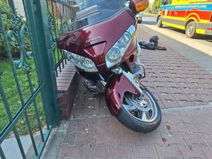 Oparty o metalowe ogrodzenie motocykl uszkodzony w kolizji.