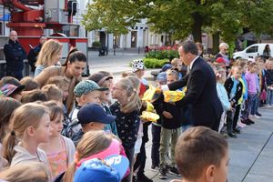 Akcja ODBLASKOWY MALUCH zorganizowana na wolsztyńskim Rynku. Organizatorzy akcji, tu Burmistrz Wolsztyna, rozdają kamizelki dzieciom.