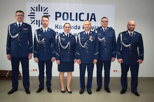 Sala Konferencyjna KPP w Wolsztynie.  I Zastępca Komendanta Powiatowego Policji w Wolsztynie pozuje do zdjęcia z gośćmi uroczystej zbiórki.