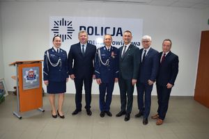 Sala Konferencyjna KPP w Wolsztynie.  I Zastępca Komendanta Powiatowego Policji w Wolsztynie pozuje do zdjęcia z gośćmi uroczystej zbiórki.