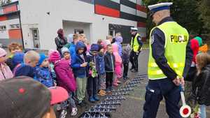 Dwaj policjanci i grupa dzieci stoją przy rozciągniętej kolczatce.