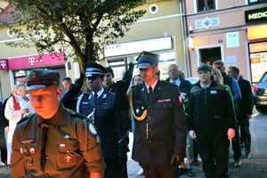 Pani Komendant w asyście Komendanta Powiatowego PSP salutuje podczas składania wiązanki pod pomnikiem.
