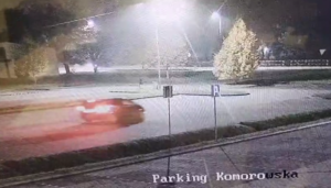 Sceneria nocna. Parking i pojazd z włączonymi światłami uchwycony w ruchu.