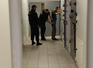 Policyjny areszt. Policjant przeszukuje osadzonego przed wydaniem w celu doprowadzenia