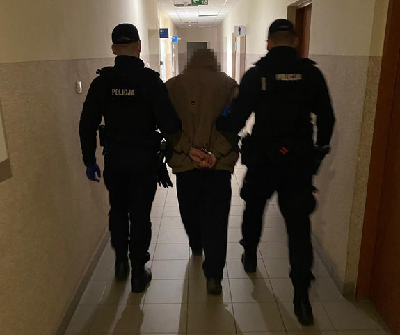 Korytarz budynku Policji. Dwaj umundurowani policjanci prowadza zatrzymanego.