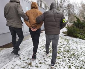 Dwaj nieumundurowani policjanci prowadzą zatrzymanego.