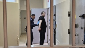 Policjant - profos sprawdza manualnie osadzonego przed przekazaniem do doprowadzenia do sądu.