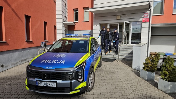 Policjanci doprowadzają zatrzymanego do sądu.